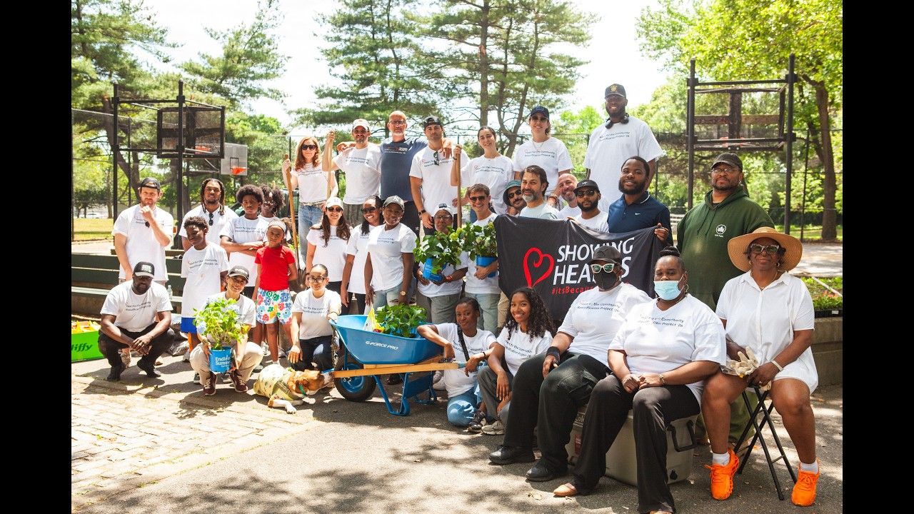 Showing Hearts volunteers gathered with plants and wheelbarrows at a community beautification project in Queens